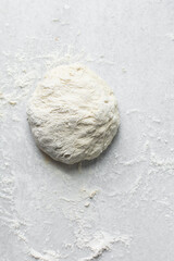 Overhead view of bread dough being shaped, Shaping proofed dough on a white surface, process of making artisan bread