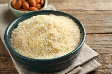 Fresh almond flour in bowl on wooden table, closeup