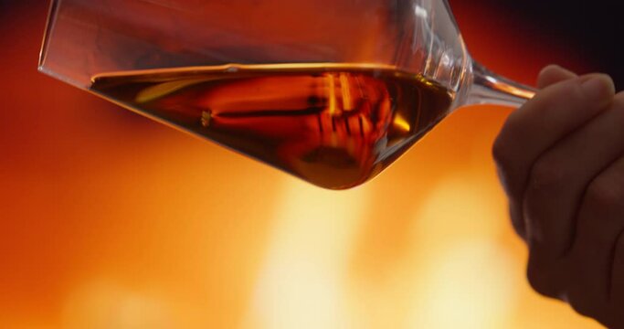 Hands holding a glass of wine against a fire bone