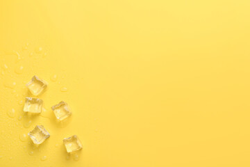 Crystal clear ice cubes on yellow background, flat lay. Space for text
