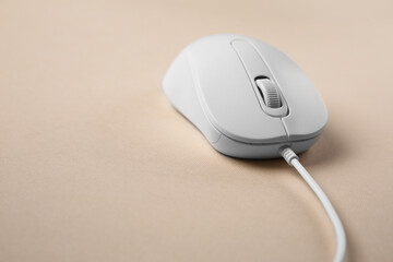 One wired mouse on beige background, closeup. Space for text