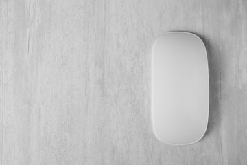 One wireless mouse on grey wooden table, top view. Space for text