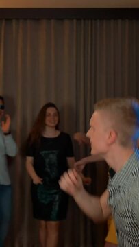 Two guys and their friends dancing at home party. Happiness, fun and crazy moving by sound music beat. 4k UHD. Slow motion Vertical shot.