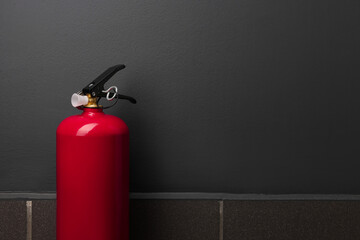 Obraz premium One fire extinguisher near grey wall, space for text