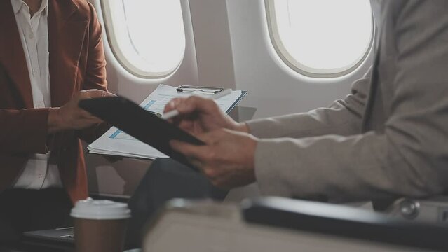 business people at meeting in private plane, asian businessman in suit discusses work with female colleague, manager shows graphs and reports to the boss, business partners fly in jet