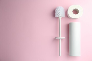 Toilet brush, holder and roll of paper on pink background, top view. Space for text