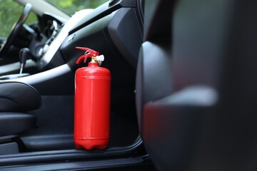 Red fire extinguisher in automobile. Car safety equipment