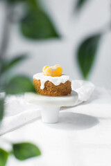 Iced mini bundt cake on a white plate, vanilla bundlette with a clementine segment on a plate, small vanilla bundt cake with an icing glaze