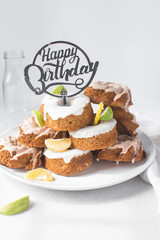 Happy birthday sign on a stack of iced mini bundt cakes, individual birthday cakes, bundtlettes stacked with a happy birthday cake topper