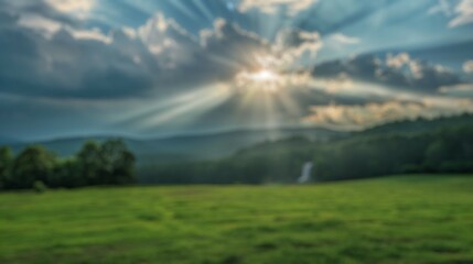 Blur background of sun shining through clouds over a fresh green field and mountain with a white...