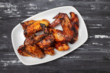 Baked chicken wings with sweet chili sauce in a plate.