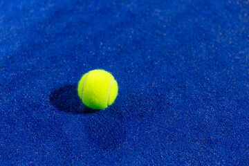 yellow padel ball on a padel blue court 