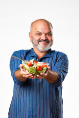Senior Indian asian man eating fresh salad. Mature male having healthy snack, healthcare, diet concept.