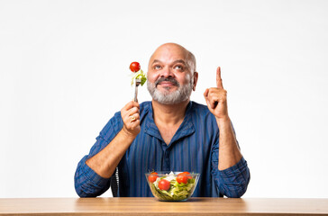 Senior Indian asian man eating fresh salad. Mature male having healthy snack, healthcare, diet...