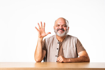 Indian asian retired old man counting numbers using fingers and showing it to camera with smile