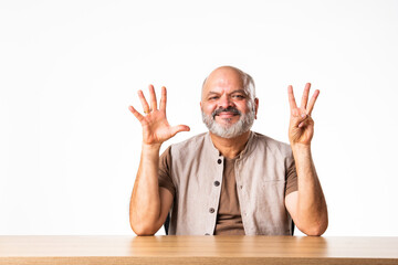 Indian asian retired old man counting numbers using fingers and showing it to camera with smile