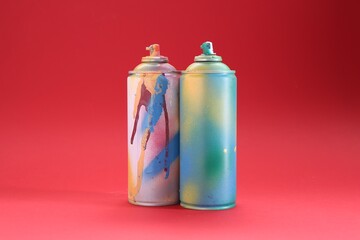 Two spray paint cans on red background