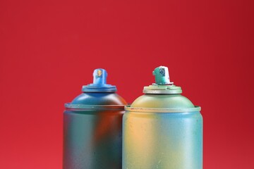 Two spray paint cans on red background