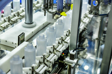 White plastic bottles in a conveyor belt on a high quality automatic vertical filling machine. in the factory production line