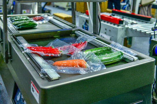 Fresh vegetables packed in a clear plastic wrap production line in factory, industrial food production