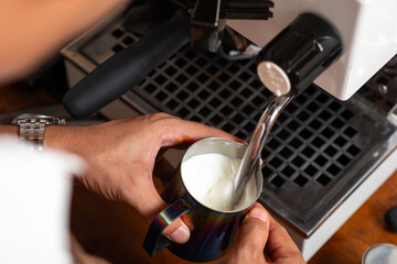 Barista Steaming Milk With a Coffee Machine Pitcher in a Modern Cafe
