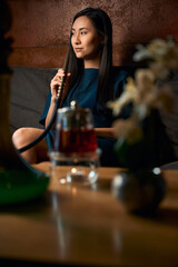 Side view attractive woman smoking hookah and drinking tea