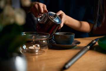 Close-up view woman pouring fresh brewed lose leaves tea