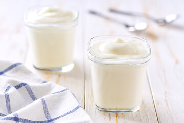 Tasty yogurt in a glass jars on a white table, selective focus.