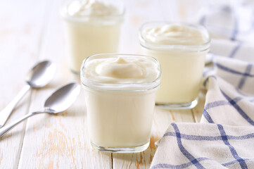 homemade organic yogurt  in a glass jars with spoons on a light table, selective focus.