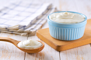 homemade organic yogurt in a ceramic bowl with spoon on a light background, selective focus.