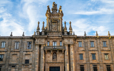 Obraz premium Baroque facade of a historical building with ornate sculptures and emblem, set against a blue sky with wispy clouds, possibly in Europe during spring