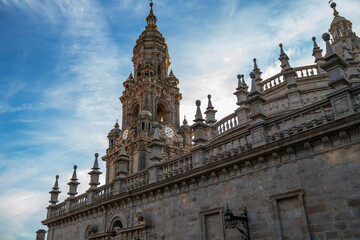 Fototapeta premium Baroque facade of a historical building with ornate sculptures and emblem, set against a blue sky with wispy clouds, possibly in Europe during spring.
