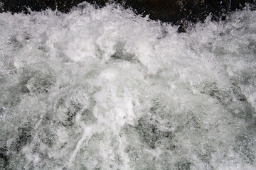 Wasser trifft auf einen Felsen und spritzt