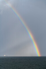 Rainbow at sea. Cargo vessel. Seascape, blue sea.
