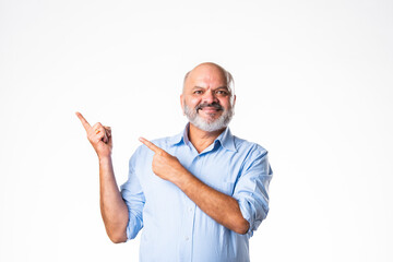 Fototapeta premium Cheerful Indian asian senior retired old man pointing finger at blank, showing something