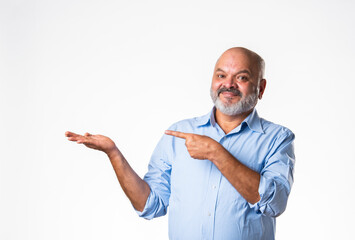 Cheerful Indian asian senior retired old man pointing finger at blank, showing something
