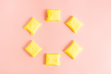 Six yellow women's pads on a pink background.