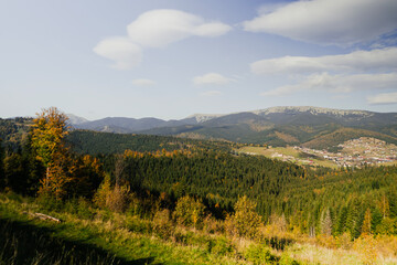 Autumn mountains with green forest and tall trees. Travel, vacation and relaxation with fresh air. View from the height of a high mountain ski resort