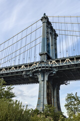Fototapeta premium view of manhattan bridge over hudson river with blue sky (long exposure downtown brooklyn skyline view) travel tourism destination new york city skyscraper