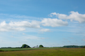 View over the fields of a white church on the horizon of a rolling landscape