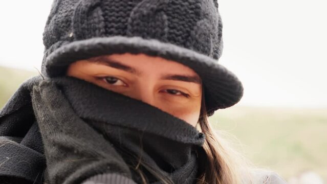 Young Caucasian Woman Wearing Black Winter Gear with Scarf Covering Face. Girl in Winter Clothes