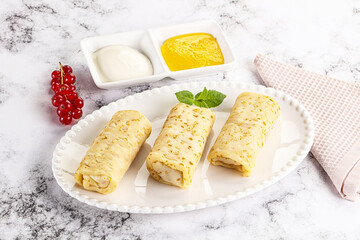 Homemade stuffed pancakes with honey and cream sour