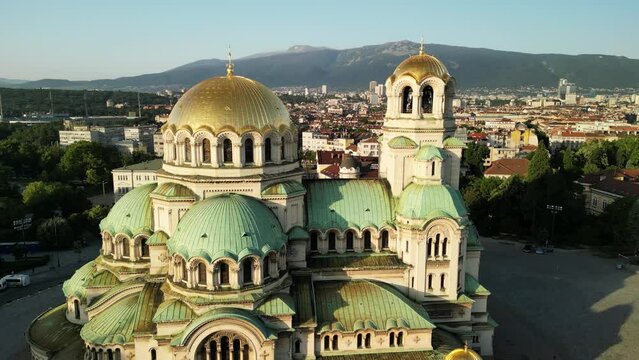 Aerial drone shot of the Cathedral St. Alexander Nevsky in Sofia Bulgaria. Bulgarian orthodox church during sunrise surrounded by green trees. Orthodox cathedral. Flying from drone.