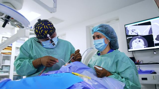 Male doctor wearing headlight applies medial surgical tools. Otolaryngologic procedure taking place in modern surgery.