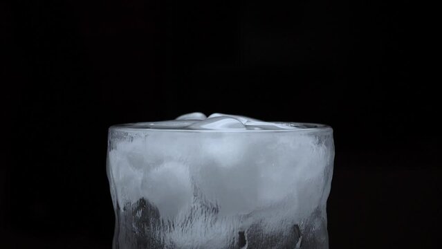 Detail Shot of Ice Cubes Falling into Glass of water. slow motion