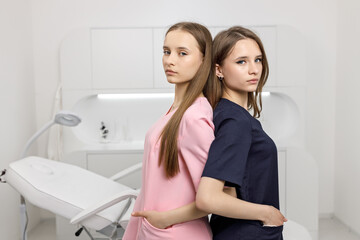 Two young female nurses in pink and blue uniforms. Woman interns