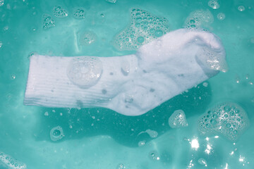 Cleaning dirty socks in basin of soapy water