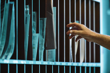 Hand reaching into organized mail sorting shelf