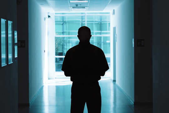 Dark hallway, man’s silhouette, bright glass exit