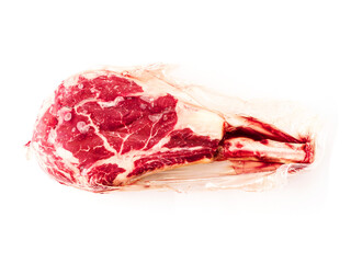 Fresh expensive tomahawk steak on the bone in a plastic vacuum package for freshness on white background. High quality beef meat product. Butcher craft. Food industry.